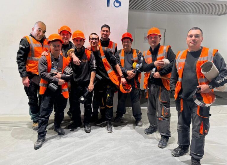 Equipo de instaladores de moquetas Disstands en Barcelona con uniforme naranja y equipamiento profesional